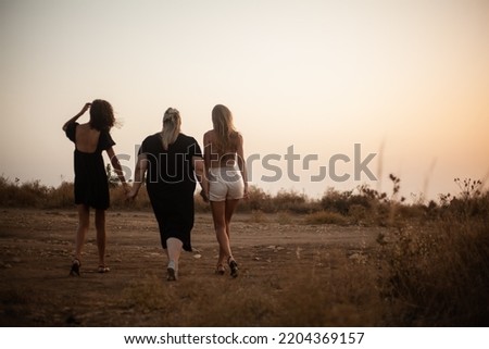 Back view of group pf three friends, plus sizewith two thin girls walking happy time together in the nature. Beautiful overweight and strong women have fun, enjoy the momet of sunset .
