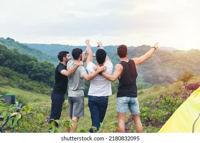 Back view of group of young man friends camping standing hugging on shoulder together and raising up his hands on mountain - Powered by Shutterstock