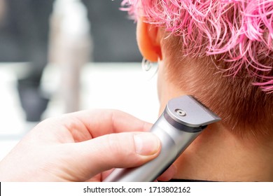 Back View Hairdresser Hand Is Shaving Pink Hair Of Woman With Electric Trimmer In Hair Salon, Close Up.