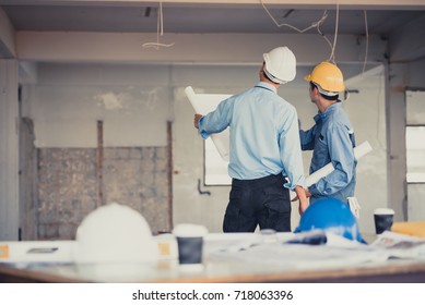 Back view of hand's engineer worker or businessman holding white safety helmet and blueprint with teamwork on site background. - Powered by Shutterstock