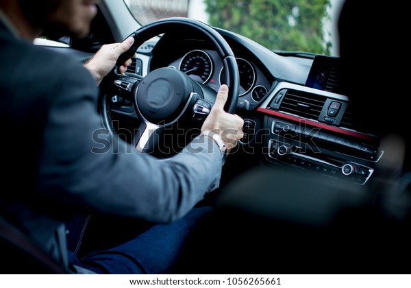 Back view of an handsome smiling business man driving\
his car