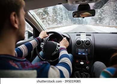 Back View Of Handsome Young Driver In Stripes Sweater Driving Through Winter Forest