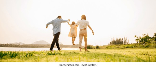 Back view of Happy Asian family walking and playing together in a scenic garden, with a beautiful sunset in the background and a feeling of fun and enjoyment, Family day - Powered by Shutterstock