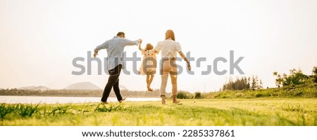 Back view of Happy Asian family walking and playing together in a scenic garden, with a beautiful sunset in the background and a feeling of fun and enjoyment, Family day