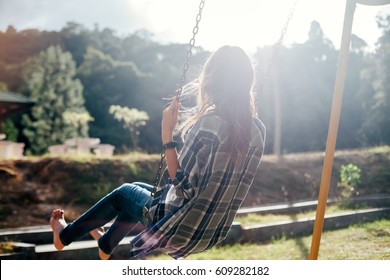 Back View Of Happy Barefoot Girl On Swing In Sun Light. Carefree Woman