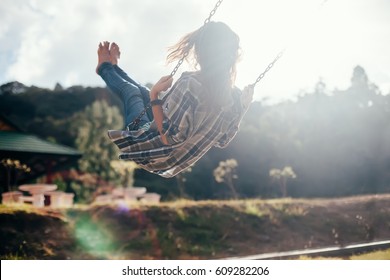 Back view of happy barefoot girl on swing in sun light. Carefree woman - Shutterstock ID 609282206