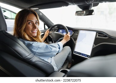 Back view happy caucasian smiling confident satisfied woman drive hold put hand on steering wheel using maps on tablet look camera sit in auto new car automobile Journey traveling lifestyle concept - Powered by Shutterstock