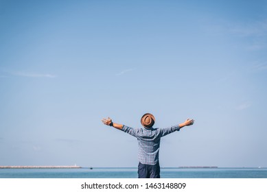 Back View Of Happy Excited Man Winner Traveler Or Hipster Raising Arms Up To Blue Sky Feeling Free Motivated Over The Beach Enjoying Beautiful View Travel On Vacation, Freedom Concept