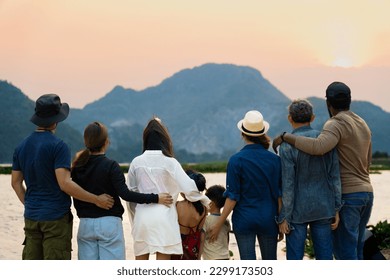 back view of happy family standing and looking at sunset behind the mountain and river beauty in nature at camping area, multi-generation travelers spend time together during weekend holiday vacation - Powered by Shutterstock