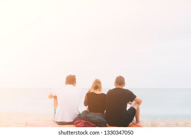 Back View Happy Friends 3 Traveler Sit On The White Sand Beach In Summer Sunset Time.Concept For Vacation, Holiday, Love Triangle And Summer Relax.