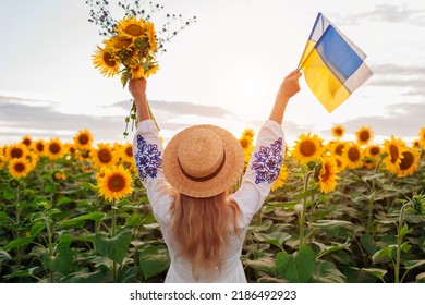 Back view of happy woman raising arms with Ukrainian flags and bouquet of sunflowers field at sunset. Peace and freedom - Shutterstock ID 2186492923