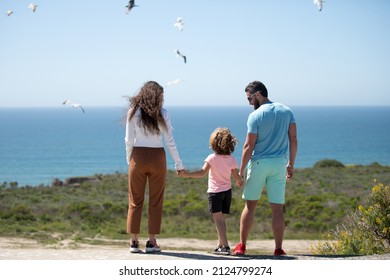 Back View Of Happy Young Family Walking On Beach. Child With Parents Holding Hands. Full Length Freedom Poeple.