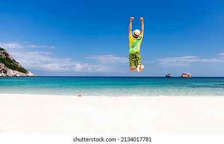 Back view of happy young man jumping with outstretched arms on the beach-Summer vacation concept - Powered by Shutterstock