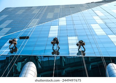 Back view high rise window workers working on glass building cleaning, work on height concept