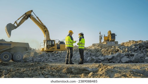 Back View Of Hispanic Female Project Manager And Caucasian Male Civil Engineer Discussing New Real Estate Project On Construction Site. Industrial Excavators Digging The Ground For Building Foundation - Powered by Shutterstock