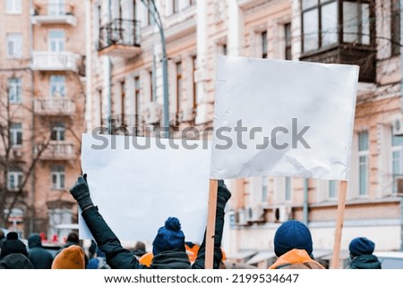 Back view of a huge crowd with white cardboard banners in their hands protesting on the street. Revolution. Demonstration. Woman. Sign. City. Street. Crowd. Freedom. Activist. Democracy. Strike