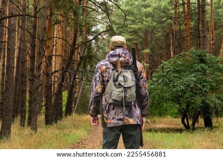 Back view of hunter with a backpack and a gun