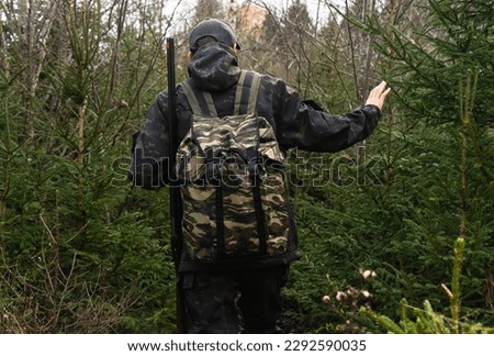 Back view of hunter with a backpack and a gun