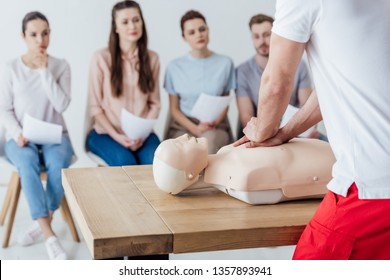 back view of instructor performing cpr on dummy during first aid training with group of people - Powered by Shutterstock