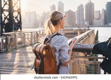 Back view of international tourist with trendy backpack enjoying time for exploring USA megalopolis - New york standing at Brooklyn district and looking around at landscape of big city area