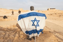Rückblick Auf Den Israelischen Soldaten Mit Weißer Und Blauer Flagge Israels Vor Dem Hintergrund Der Wüste Und Felsen. Militärische Männer, Die Versprochenes Land Beschützen. Nationalflagge Israels. Kriegskonflikt