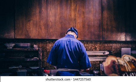 Back view of a Japanese chef preparing foods at a Robatayaki restaurant.