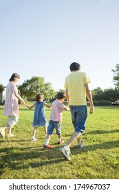 Back View Of Japanese Family Walking In The Park Holding Hands