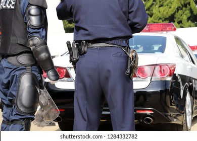 Back View Of Japanese Police Officers With Patrol Car