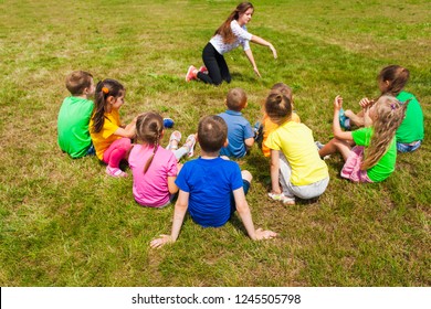 Back View Of Kids Sitting On A Grass Playing Charades