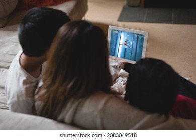 Back View Of Latin Mother And Children At Home Watching Swimming Event On Tablet. Sports, Competition, Entertainment And Technology Concept Digital Composite Image.