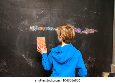 Back view of a little boy cleaning chalkboard.