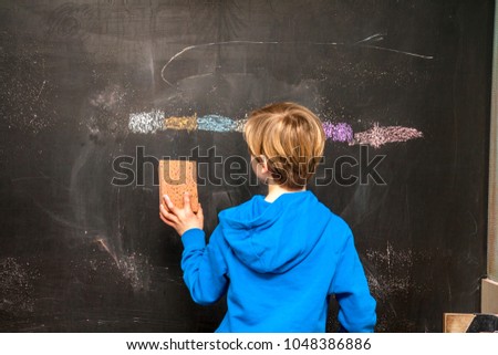 Back view of a little boy cleaning chalkboard.