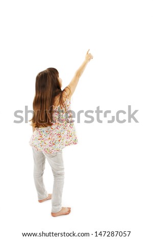 Back view of little girl points at wall. Rear view. Isolated on white background