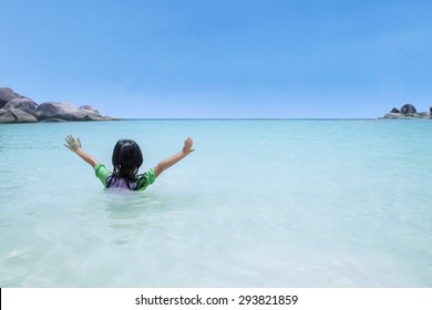 Back View Of Little Girl Swimming And Playing Alone On The Beautiful Beach