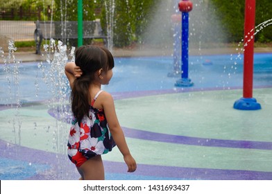 Back View Of The Little Girl In Swimsuit Going At The Splash Pad