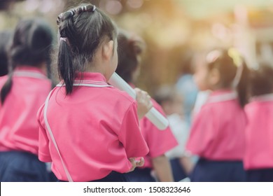 Back View Of Little Girls Use Paper Rolls Instead Of Long Cheerleader Baton Sticks For School Parade Marching Practice.