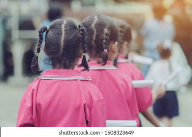 Back View Of Little Girls Use Paper Rolls Instead Of Long Cheerleader Baton Sticks For School Parade Marching Practice.