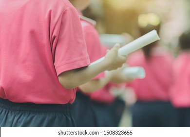 Back View Of Little Girls Use Paper Rolls Instead Of Long Cheerleader Baton Sticks For School Parade Marching Practice.