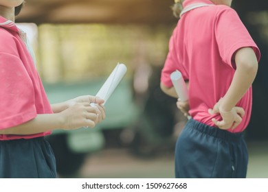 Back View Of Little Girls Use Paper Rolls Instead Of Long Cheerleader Baton Sticks For School Parade Marching Practice.