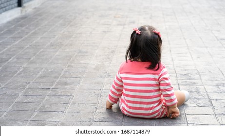 Back View Of Little Toddler Girl Is Sitting Down On The Floor Outside.baby Outside Activity.

