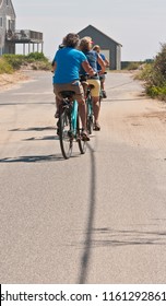 Back View, Long Distance Of A Group Of Senior Adults Bike Riding On The Back Roads Of Nantucket Island On An Autumn, Sunny, Morning