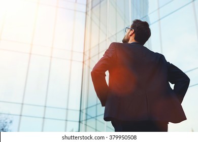 Back view of male architect looking on designed by him modern bank building while standing outside, intelligent young businessman dreaming about prosperity of his company after important meeting  - Powered by Shutterstock