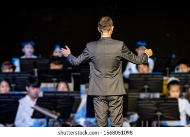 Back View Of A Male Band Conductor In Formal Suit Conducting His Concert Band