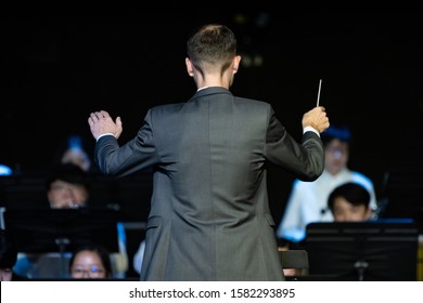 Back View Of A Male Band Conductor In Formal Suit Conducting His Concert Band