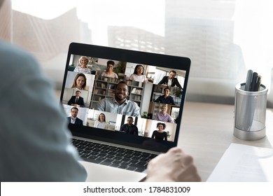 Back view of male employee have online video call on laptop with diverse multiethnic colleagues, man worker involved in webcam conference or virtual event on computer with multiracial businesspeople
