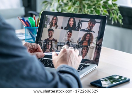 Photo of Back view of male employee speaking on video call with diverse colleagues on online briefing with laptop at home.