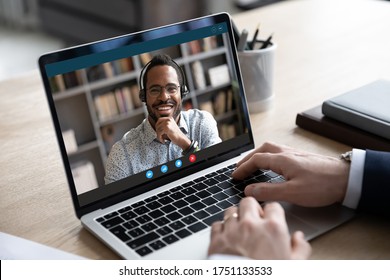 Back view of male employee talk on video call with smiling african American colleague or client, businessman have webcam online team briefing or meeting, engaged in web conference with partner