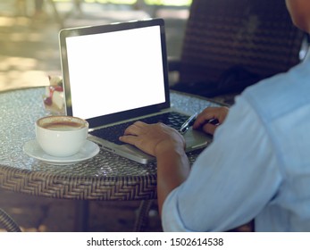 Back View Of Male Person Sitting Front Open Laptop Computer.In Your Hand Holding A Cup Of Coffee