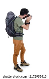 Back view of a male tourist with backpack taking a picture with the camera isolated on white background. Rear view of mountaineer photographer taking picture. 
				