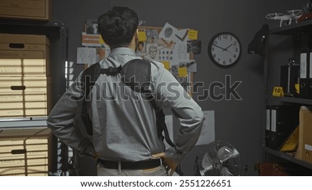 Back view of a man with a backpack standing in a detective's office, surrounded by files and investigation boards.